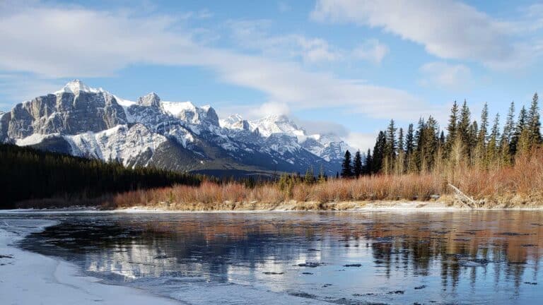 A river in winter with the Rocky Mountains in the background.